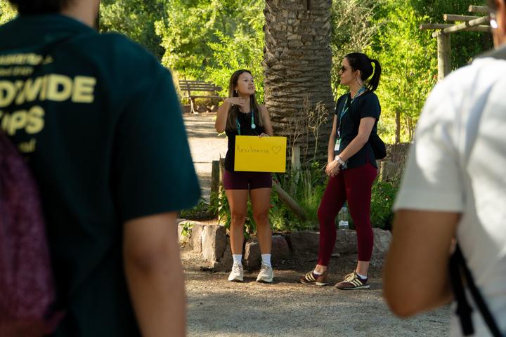 Facilitadora guiando una actividad al aire libre con un cartel que dice Resiliencia
