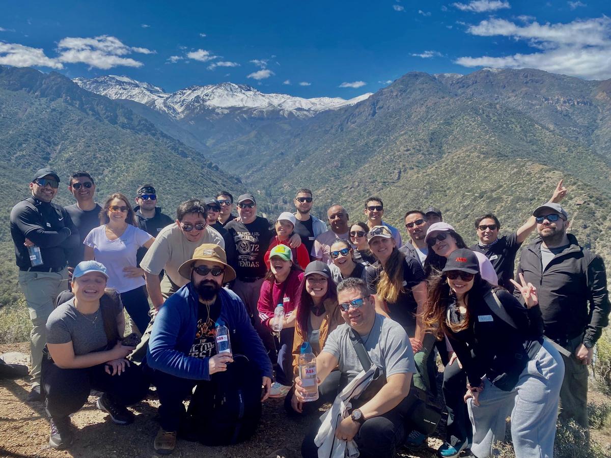 Equipo celebrando en un mirador de la cordillera con montañas nevadas de fondo