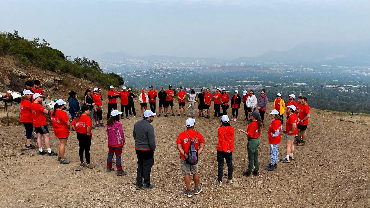 Equipo reunido en círculo en un mirador sobre Santiago durante una jornada de trekking